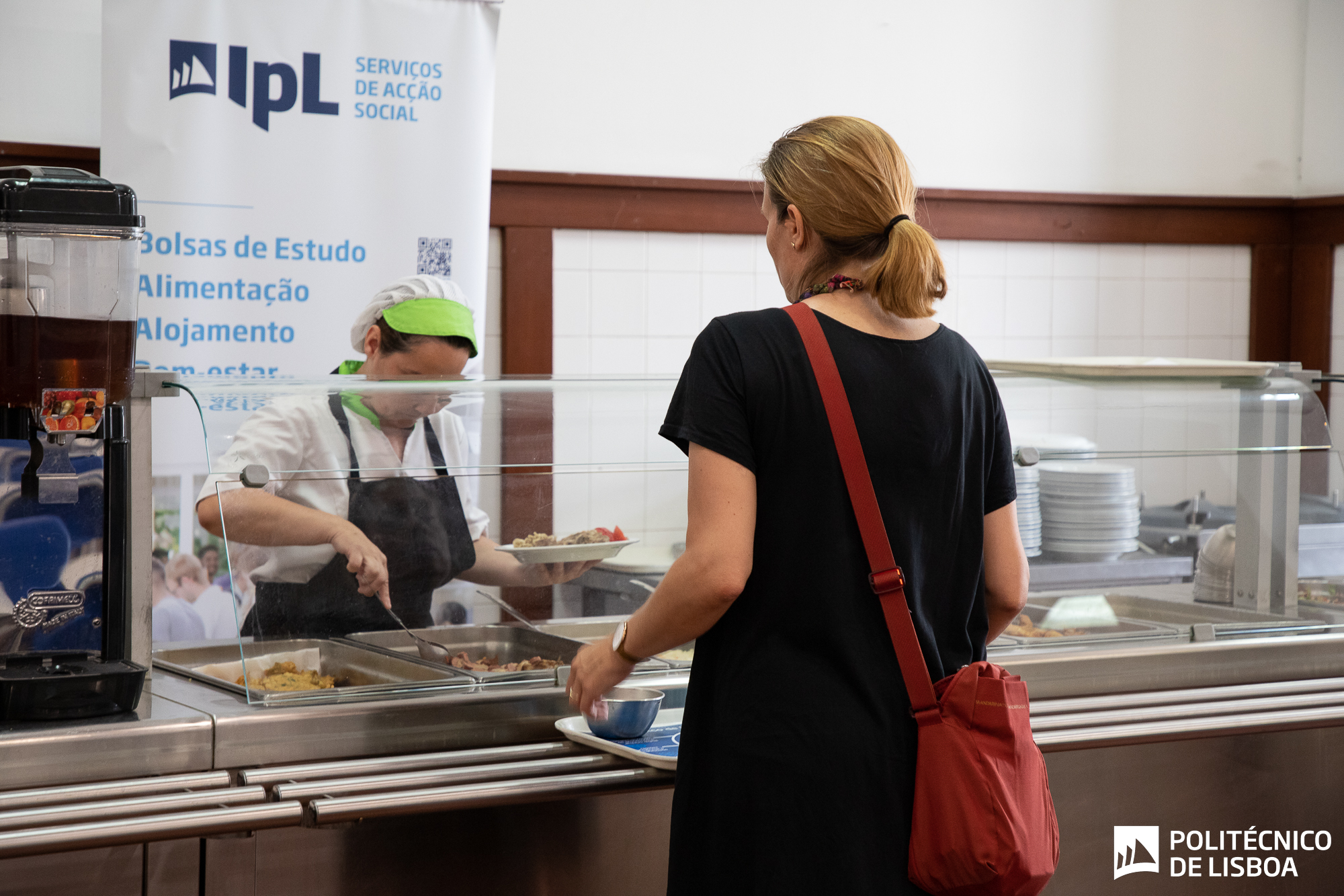 foto de uma cantina com a funcionária que serve e o utilizador com o tabuleiro