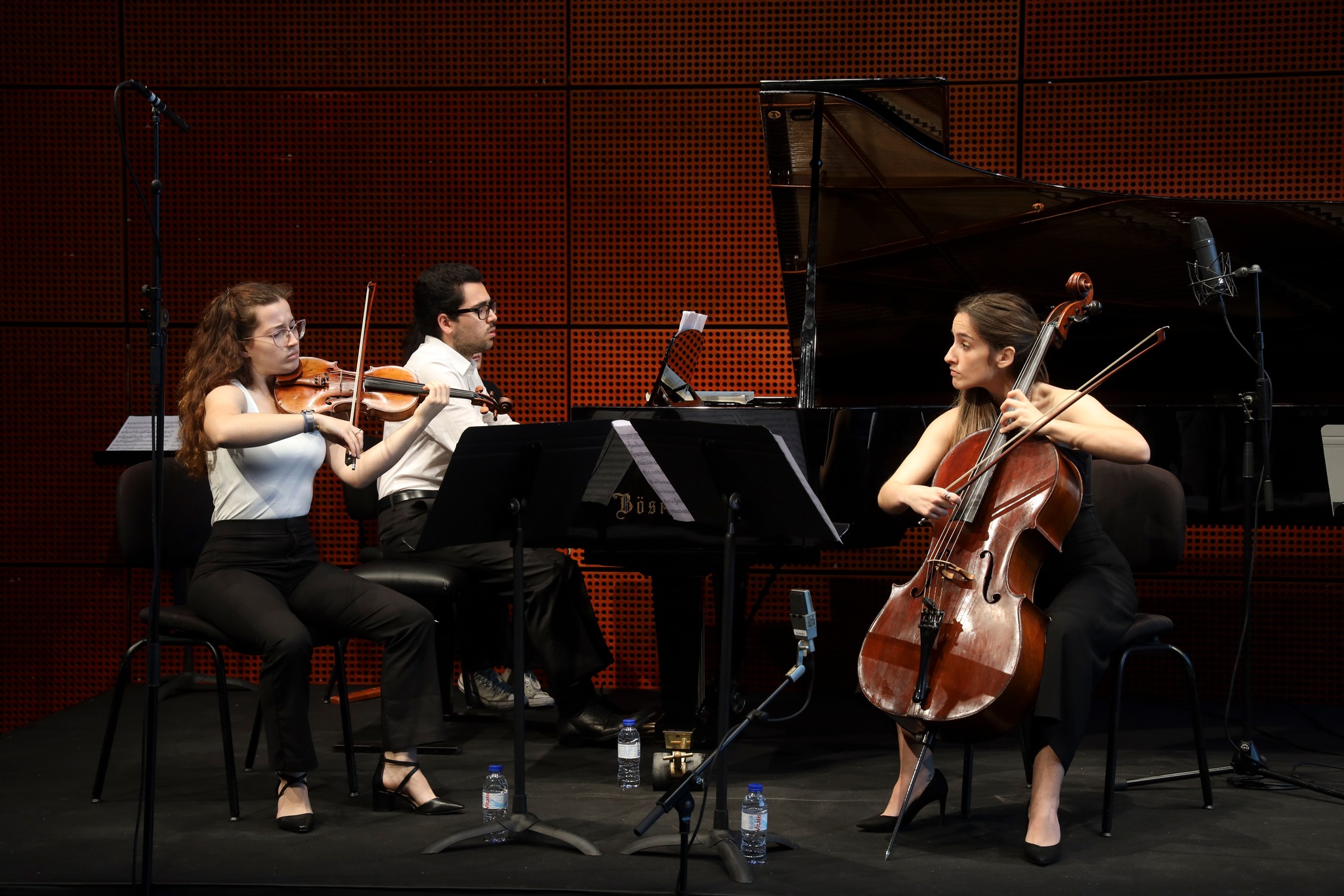 duas raparigas a tocar violoncelo e violino e um rapaz a tocar piano