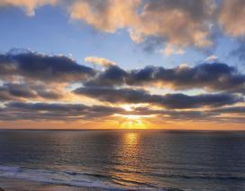 fotografia onde se vê o mar e o pôr de sol