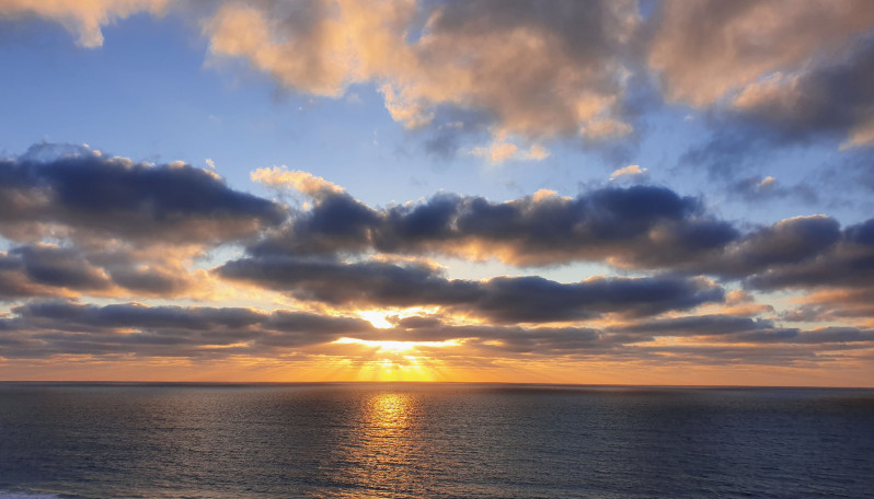 fotografia onde se vê o mar e o pôr de sol