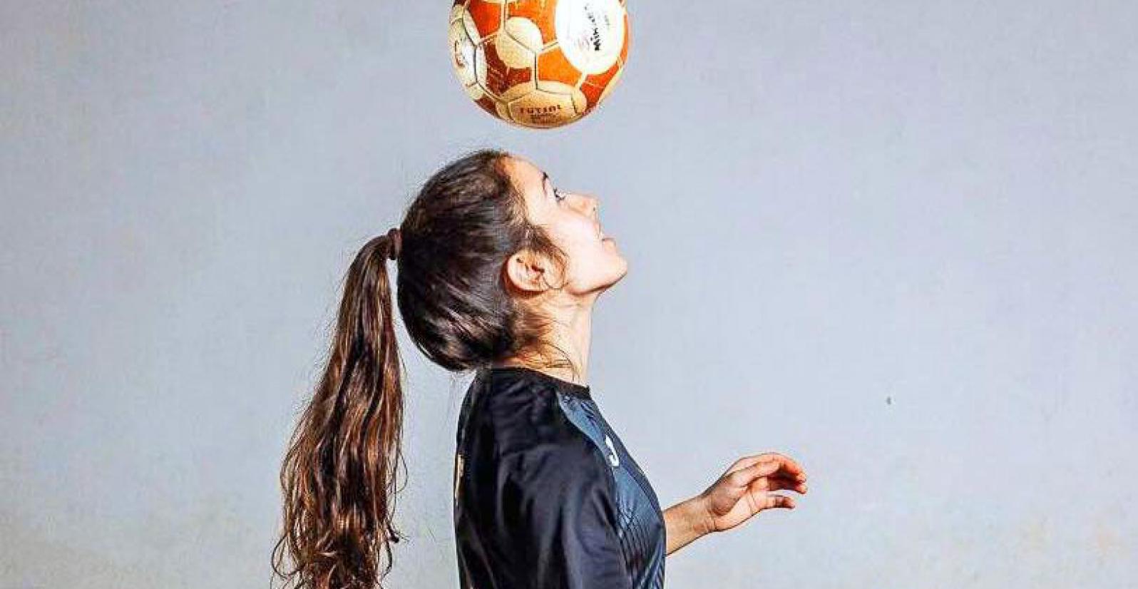 jogadora equipada a tocar com a cabeça numa bola de futsal