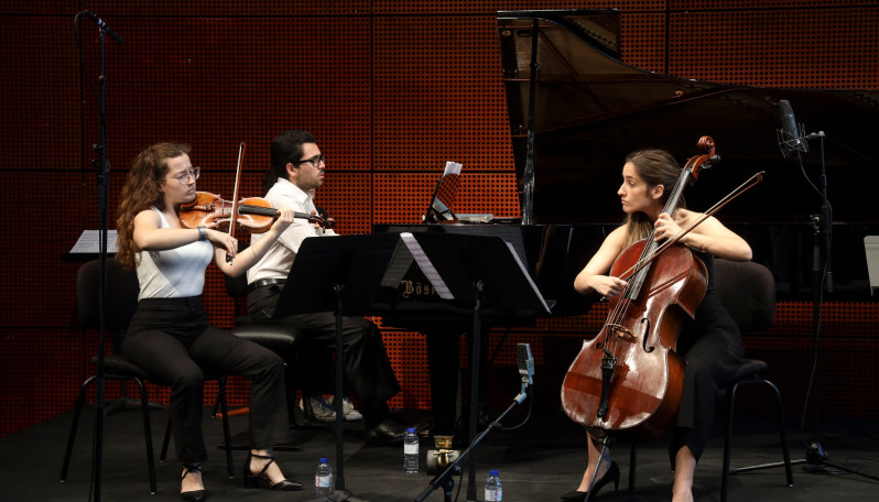 duas raparigas a tocar violoncelo e violino e um rapaz a tocar piano