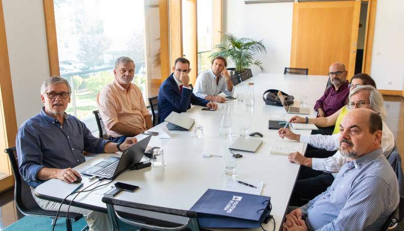 pessoas sentadas a uma mesa de reuniões numa sala 