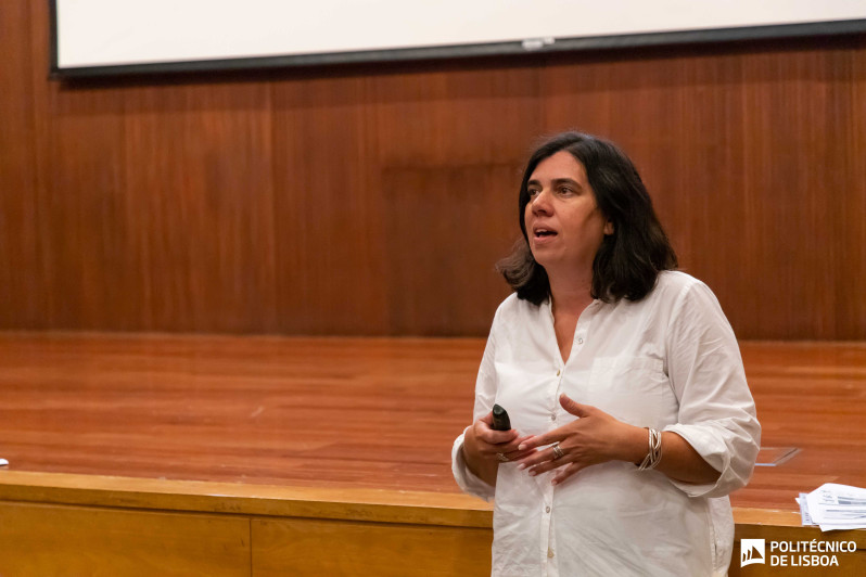 mulher de pé a falar junto a um palco