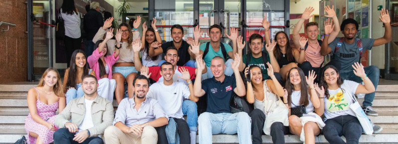 estudantes sentados nas escadas de um edifício de mãos no ar