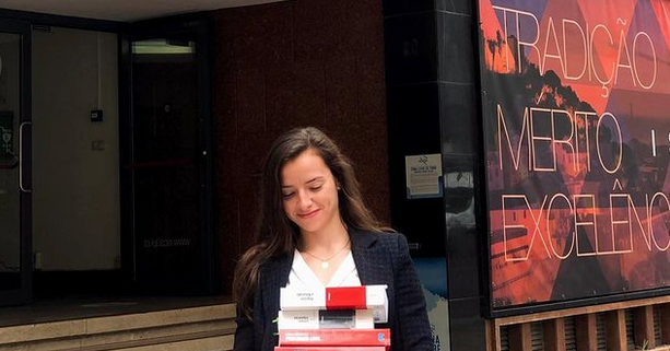 rapariga a segurar livros à frente do edifício do ISCAL