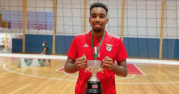 rapaz vestido com o equipamento desportivo do Benfica a segurar uma taça