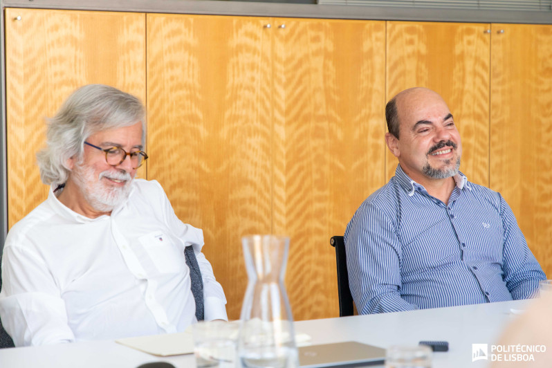 dois homens sentados a uma mesa de reuniões 