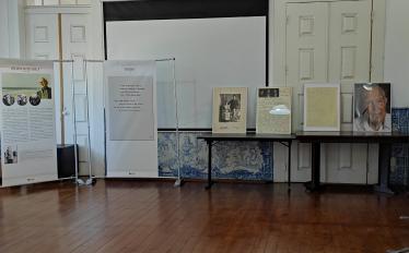 imagem da biblioteca de Vila Franca de Xira, onde se vê dois roll-ups e uma mesa com suportes a4 com imagens e informações sobre Arquimedes da Silva Santos
