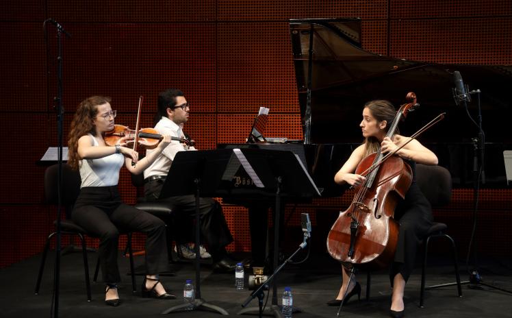 duas raparigas a tocar violoncelo e violino e um rapaz a tocar piano